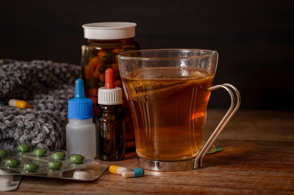 Cup of herbal tea surrounded by vitamins, supplements, and a cozy blanket, emphasizing preventive health and wellness.