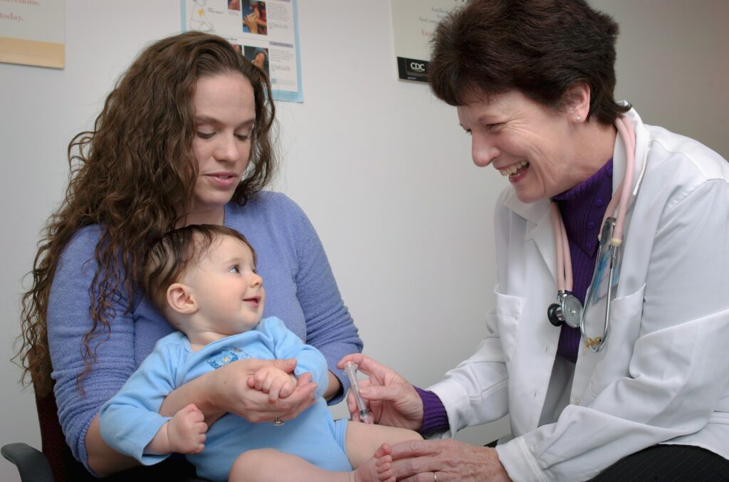 Mother holding smiling baby during a primary care visit with a clinician, emphasizing personalized healthcare and patient engagement.