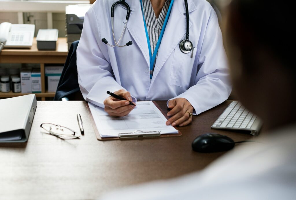Doctor in a white coat taking notes on a clipboard during a patient consultation, emphasizing the importance of building a relationship with a primary care physician.