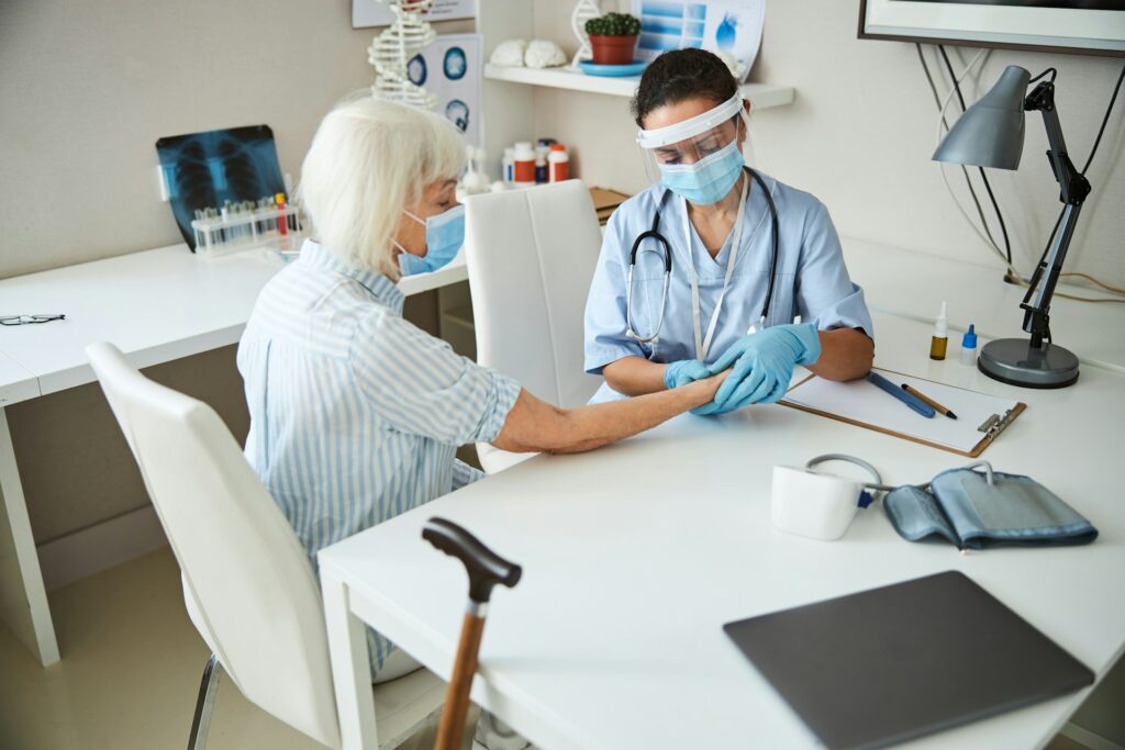 Doctor providing care to elderly patient in a medical office, emphasizing personalized primary care and health management.