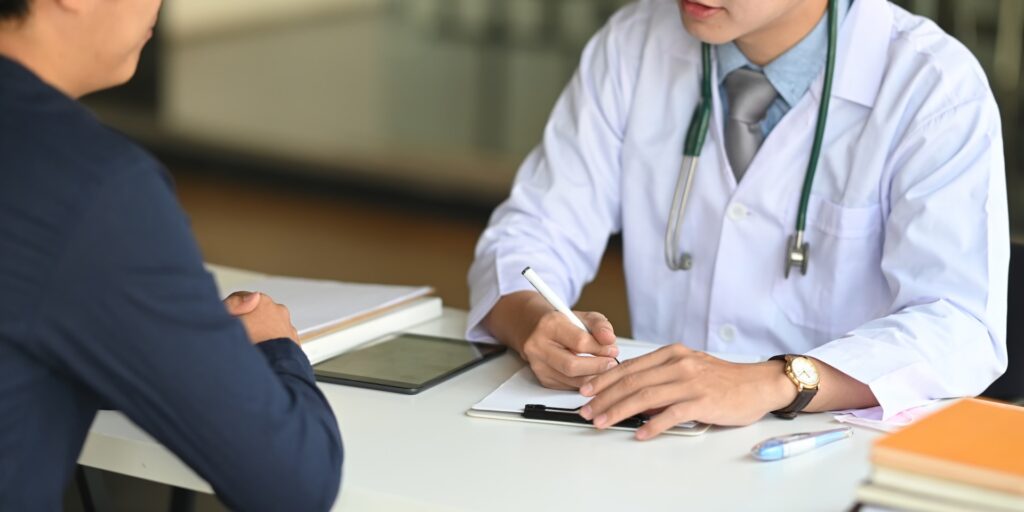 Doctor in a white coat consulting with a patient about cholesterol checks, taking notes on a notepad, emphasizing preventive care and heart health.