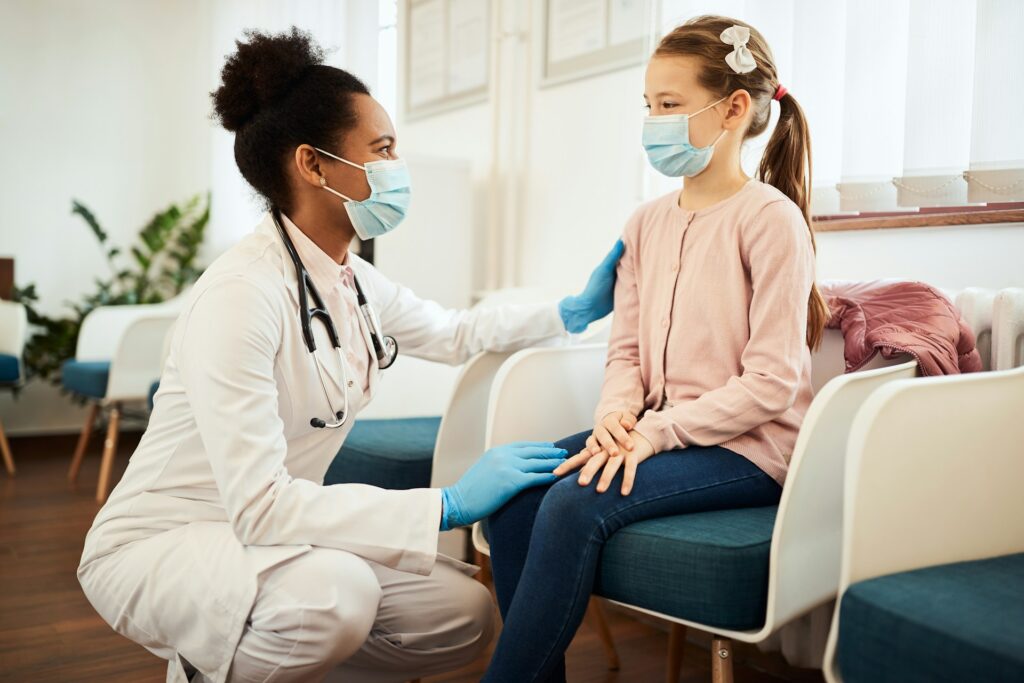 Pediatrician consulting with young girl in medical office, emphasizing personalized healthcare and building a health home for children.