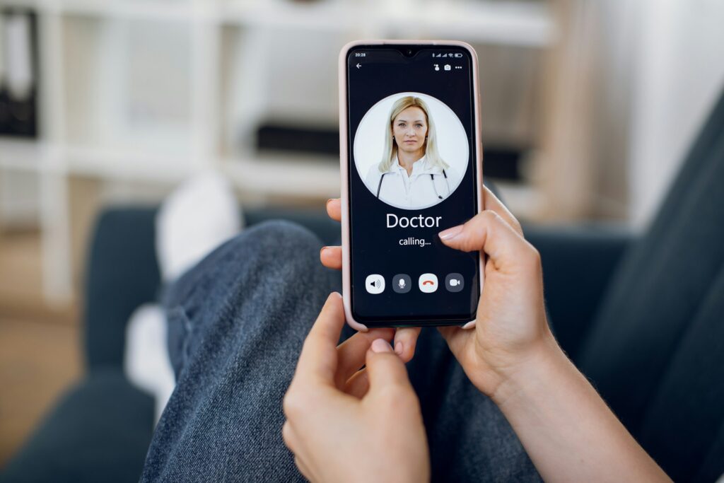 Person holding smartphone displaying a video call with a doctor, emphasizing virtual primary care appointment convenience and accessibility.